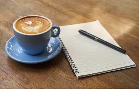 káva a zápisník s perom na stole